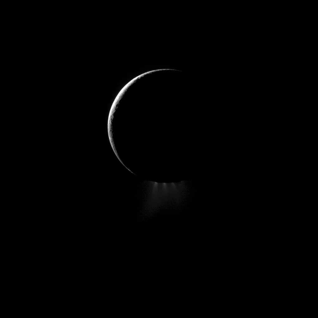 Crescent view of Saturn's moon Enceladus with water-ice plumes illuminated above its south pole