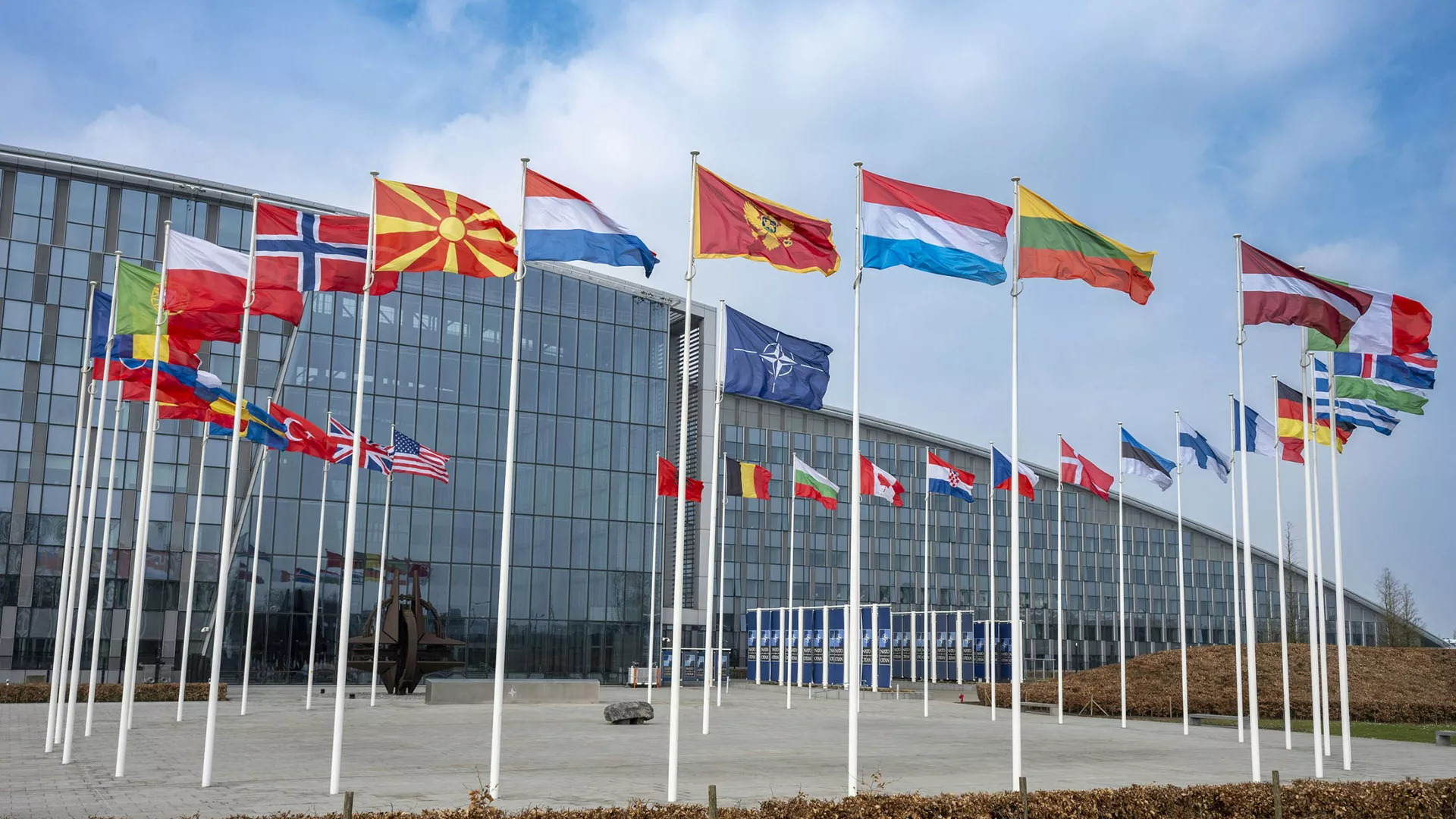 NATO headquarters in Brussels with the NATO flag and flags of member countries outside the building