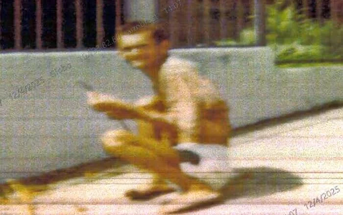 Grainy photograph of Luíz Antônio de Paula, known as Mudinho, crouching near a wall, as broadcast by Brazilian media