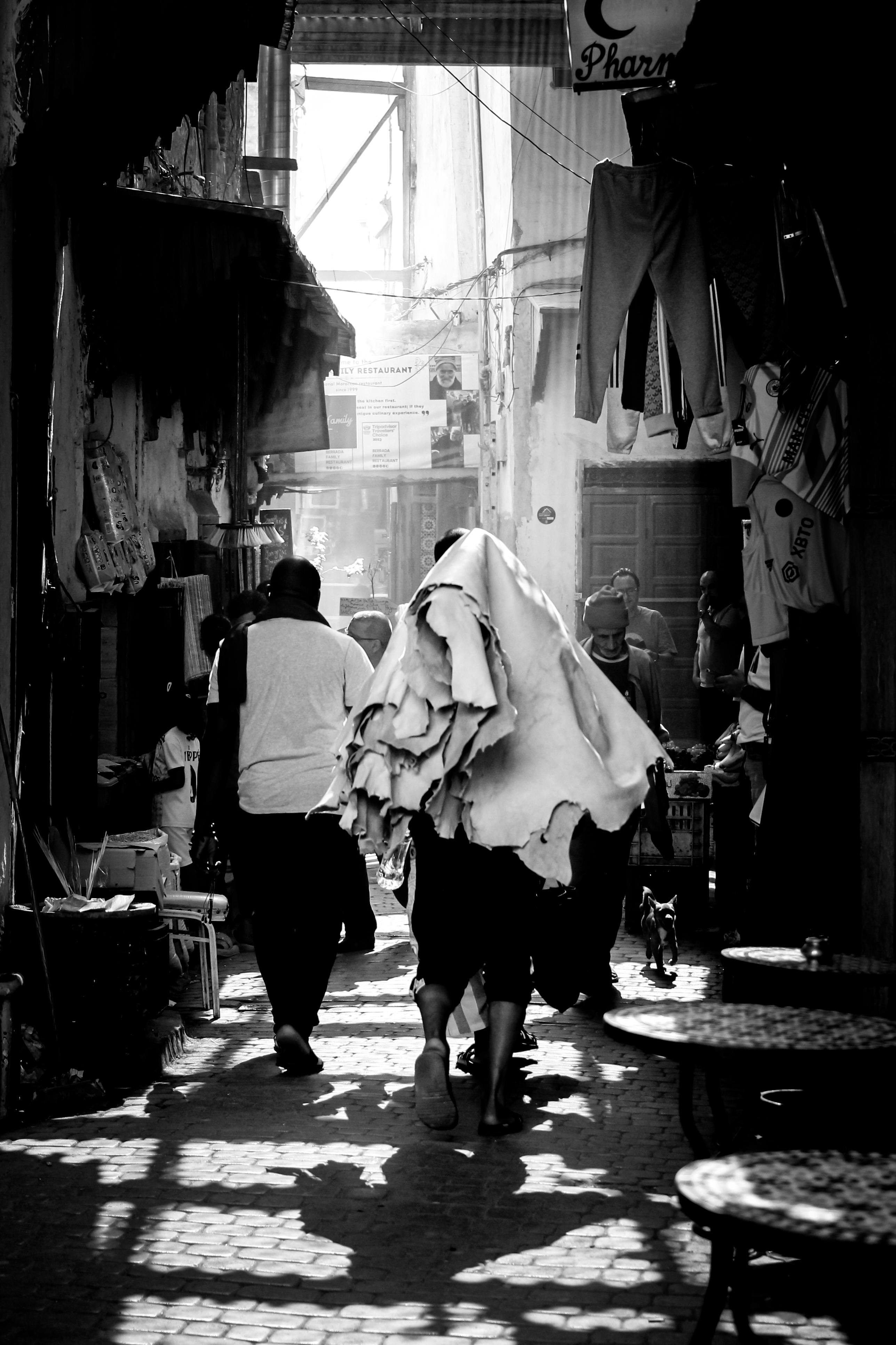 Tannery worker carrying cured hides through the medina of Fes